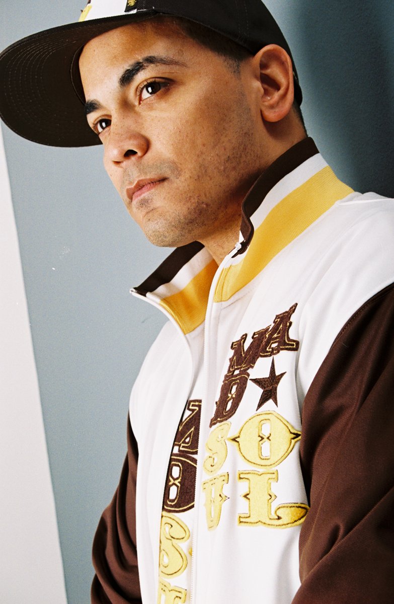 Studio portrait of a model in the brown, white and gold Madsoul track jacket