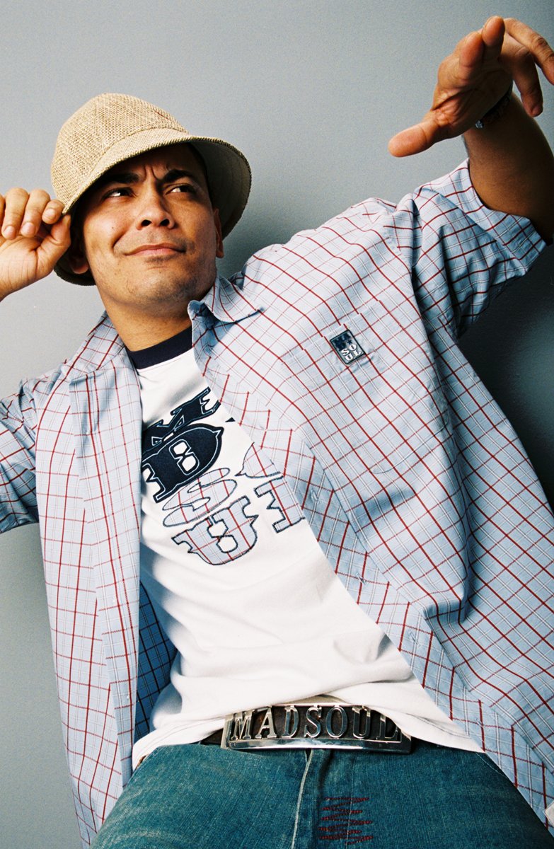 Model in a plaid shirt over a graphic tee with the chrome Madsoul belt buckle